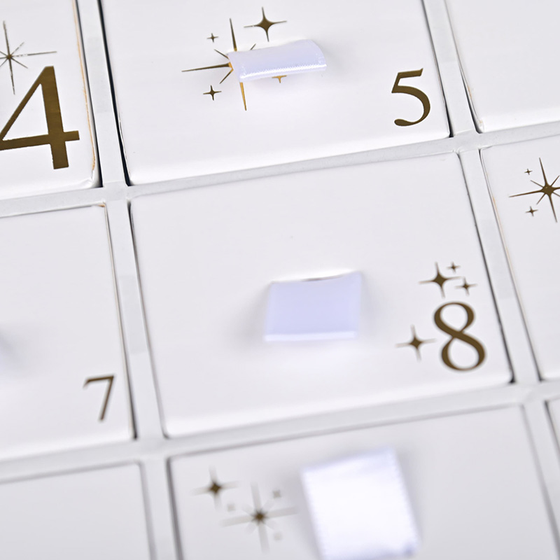Close-up de petits tiroirs dans un calendrier de l'avent de bijoux avec ruban blanc tirez onglets et chiffres d'or