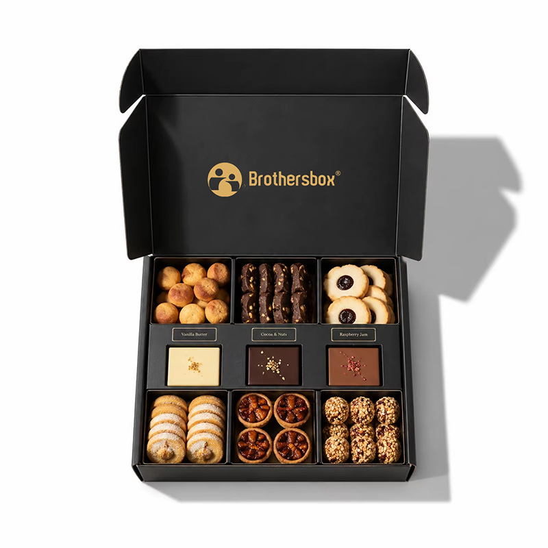 Top view of open black mailer style box with multi-compartments for nuts and sweets.