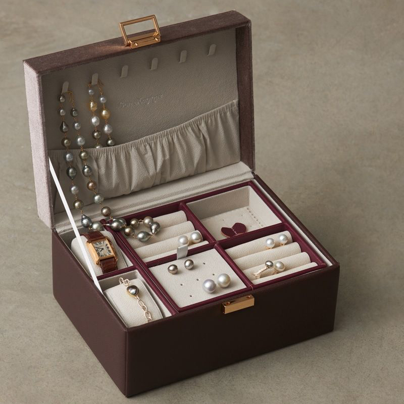 The image showcases an open, square - shaped jewelry box with a dark brown outer shell and a light - toned, velvety interior.