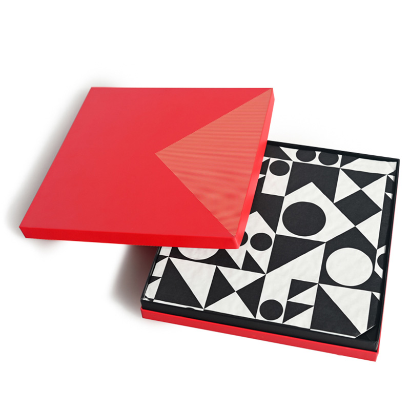 Caja de regalo de trufa de chocolate rígida cuadrada roja abierta con papel estampado geométrico blanco y negro en el interior.