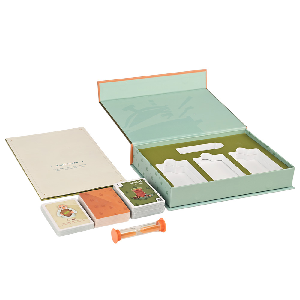 Contenido completo del juego de mesa "Daim & Amer", incluidas las cartas, el temporizador de reloj de arena y el tablero de juego.