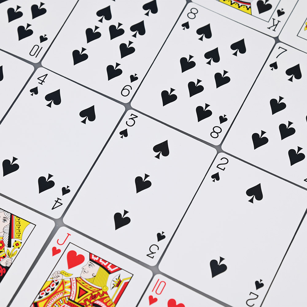 Close-up of custom printed poker card faces showing clear spade and heart suit details.