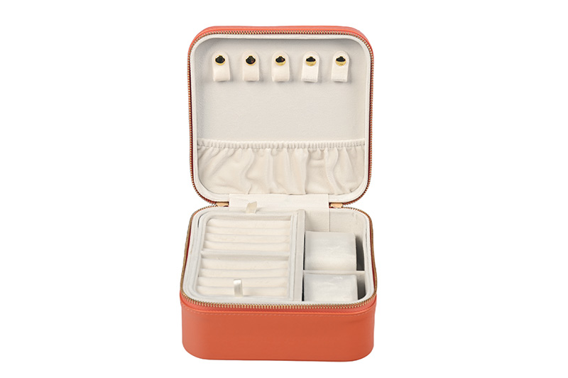 Disparo de alto ángulo de una funda de joyería de viaje de cuero naranja premium que destaca la textura acolchada.