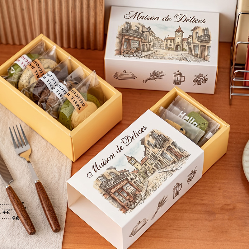 Dos cajas de envasado de alimentos semicirculares personalizadas en una mesa de comedor, una que muestra galletas envueltas individualmente en el interior, con elegantes cubiertos cerca.