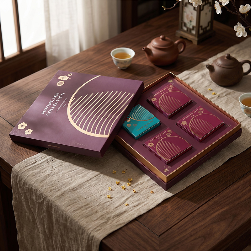 Abra a caixa de presente de embalagem de mooncake tradicional vermelho profundo em uma mesa de madeira com jogo de chá e flores secas.