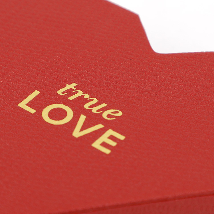 Macro shot of gold foil stamping true LOVE on textured red paper