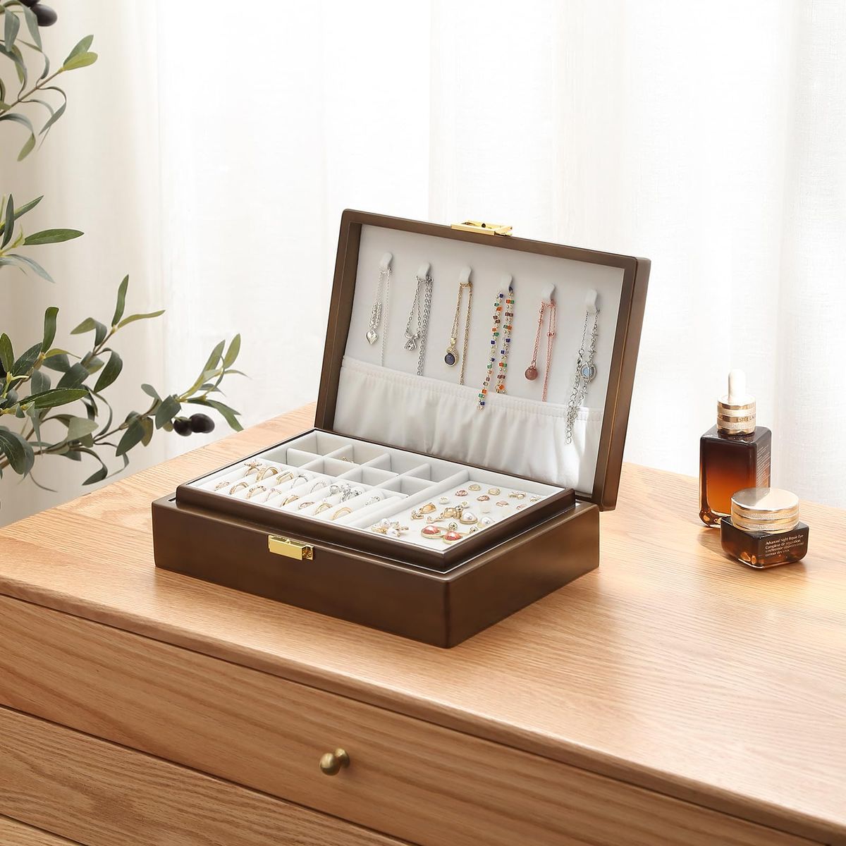 The image shows an open, dark - brown wooden jewelry box placed on a light - colored wooden dresser.