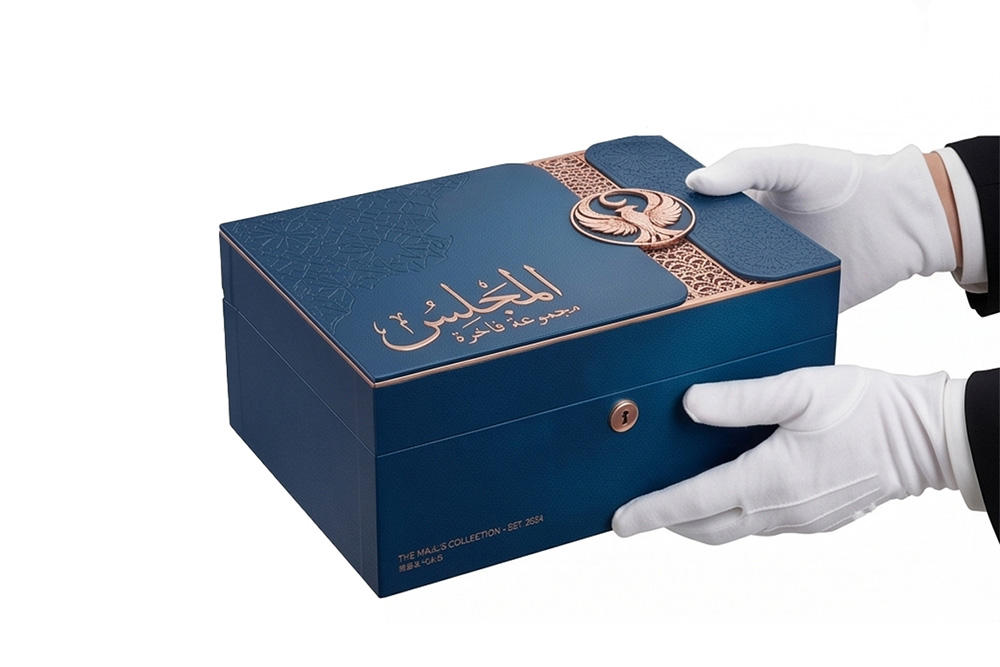 Une paire de mains gantées tenant avec élégance et présentant un humidificateur à cigares luxueux en cuir bleu, fermé, orné d’un texte arabe doré et d’un logo à l’aigle, mettant ainsi l’accent sur un cadeau d’exception.