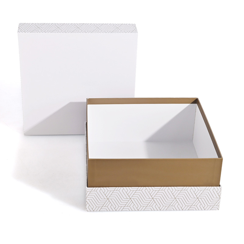 Boîte à parfum Brothersbox à motifs dorés ouverte avec couvercle à motifs debout derrière la base bordée d'or.